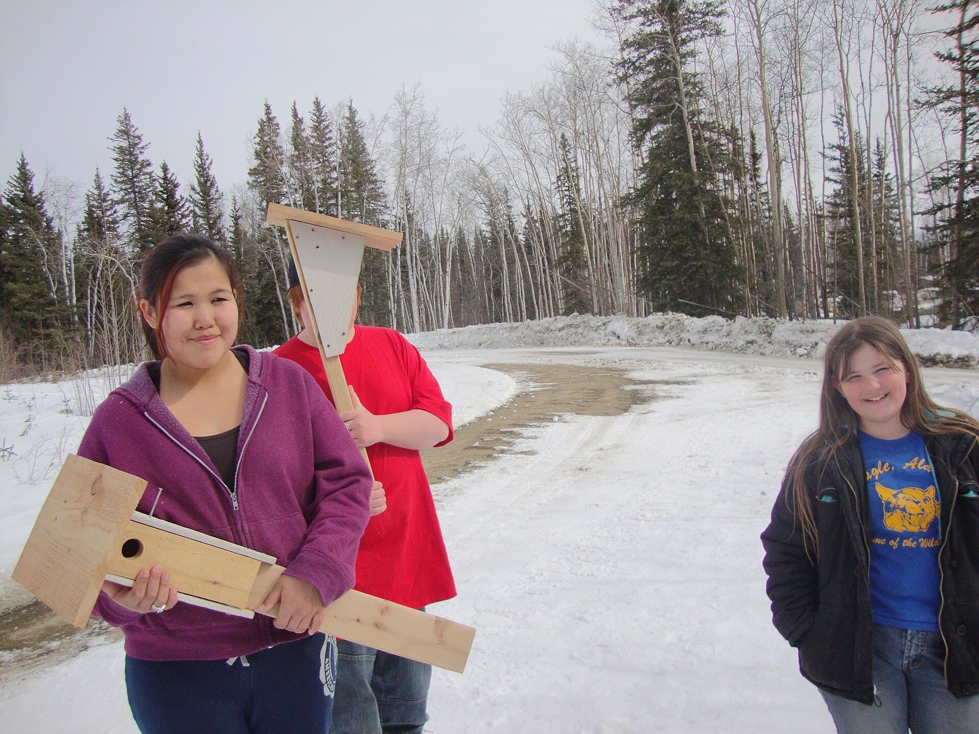 Volunteers carrying hand-built timber nest boxes.